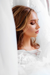 Back view of a young woman in wedding dress looking at bridal gowns on display in boutique