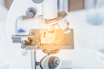 Close up of microscope at the blood laboratory. Science, biology, pharmacy concept..Orange lighting and blue filter.