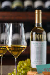 white wine in glasses on the background of green grapes and a bottle of wine