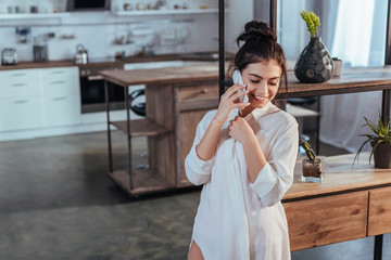 smiling girl talking on smartphone during morning time at home