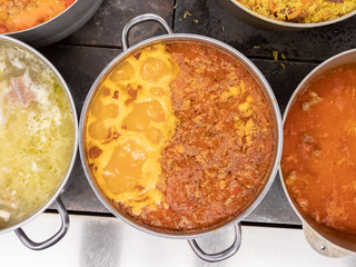 Boiling lentil soup in a large pan on the stove, next to other soups, top view