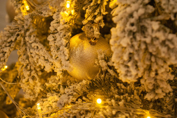 Christmas ball and garland on the Christmas tree. the garland shines with a golden, yellow warm light. Christmas, Christmas background for cards, greetings. Christmas holiday atmosphere