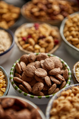 Close up and selective focus. Composition of different kinds cereals placed in ceramic bowls with cornflakes, granola, cereals and oatmeal. Flat lay, top view on white wooden table.