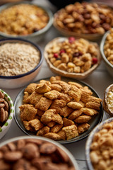 Obraz na płótnie Canvas Close up and selective focus. Composition of different kinds cereals placed in ceramic bowls with cornflakes, granola, cereals and oatmeal. Flat lay, top view on white wooden table.