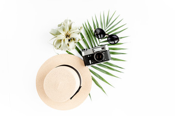 Traveler accessories on white background with retro camera, straw hat, sunglasses, and tropical palm leaf. Travel concept background. Flat lay. Top view