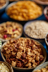 Assortment of various kinds cereals placed in ceramic bowls with cornflakes, granola, cereals and oatmeal. Flat lay, top view on blue rusty table with copy space in the middle. Selective focus.