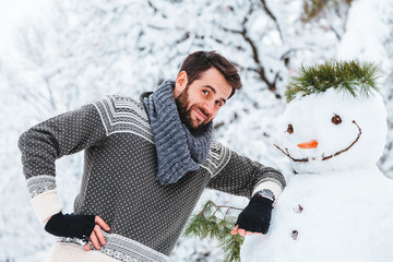 Young man making snowman in the park