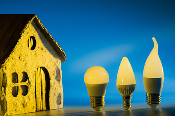 Led lamps stands near the house layout on a blue background