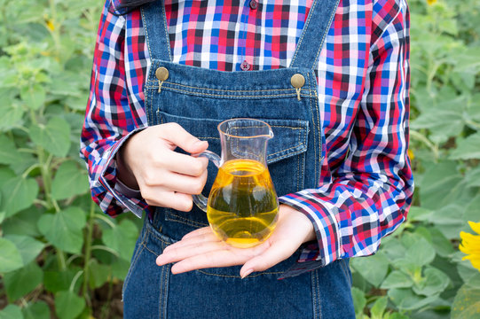 Young women bottle of oil against sunflowers - Image