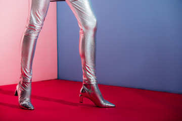 partial view of fashionable model posing in trendy silver footwear on pink and blue background