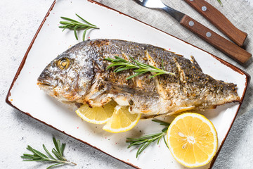 Baked dorado fish with lemon and rosemary top view.