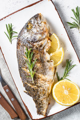 Baked dorado fish with lemon and rosemary top view.