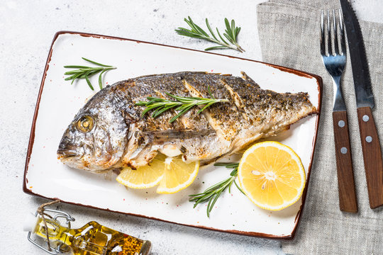 Baked dorado fish with lemon and rosemary top view.