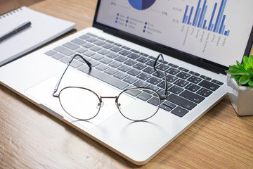 Photos of the desk with a laptop and glasses on a wooden table.