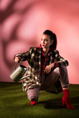 beautiful woman in fashionable checkered suit posing with watering can