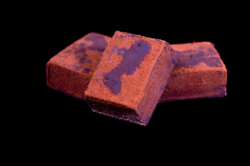 Group of little pieces of soft dark chocolate on black background