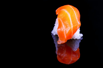 Closed up texture salmon sushi with reflection on isolated black background.