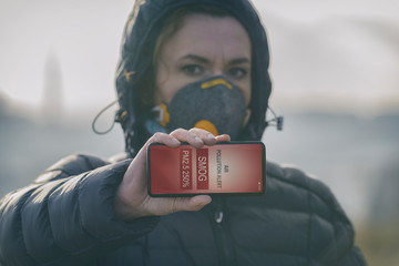 Woman wearing a real anti-smog face mask and checking current air pollution with smart phone app