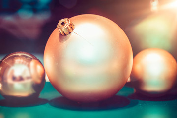 Drei goldene Weihnachtskugeln auf Tisch auf türkis - grünem Hintergrund
