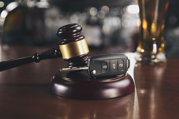Car key and beer alcoholic drink in a glass on a brown wooden table. Do not drink or drive an...