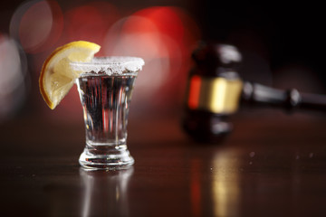 The concept of a DUI. Law hammer, alcohol and car keys on wooden table, dark background
