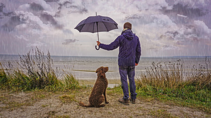 Mann schützt Hund vor dem Regen mit einem Regenschirm, Symbol für Freundschaft, Zusammenhalt,...