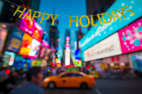Happy Holidays message hanging in front of defocus abstract blur view of the lights of Times Square, New York City, USA