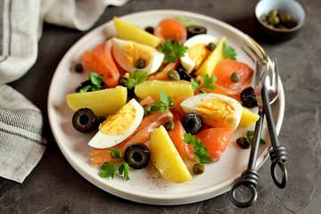 Salad of salted salmon, boiled potatoes, chicken eggs with olives, capers, parsley and olive oil.