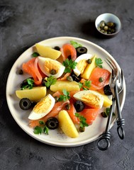 Salad of salted salmon, boiled potatoes, chicken eggs with olives, capers, parsley and olive oil.