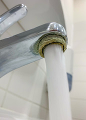 Drinking water runs from a calcified faucet