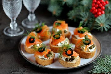 Canapes with cream cheese, salted salmon, capers, olives and dill.