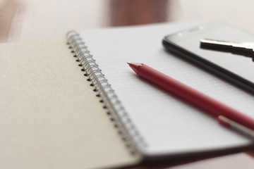 Notepad, key, phone and writing pen on the table