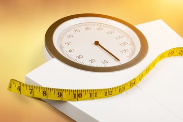 Bathroom scale with a measuring tape on background