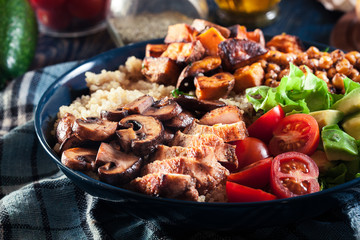 Vegetable buddha bowl lunch with chicken and quinoa, chickpea, mushrooms, lettuce and tomatoes
