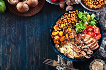 Vegetable buddha bowl lunch with chicken and quinoa, chickpea, mushrooms, lettuce and tomatoes