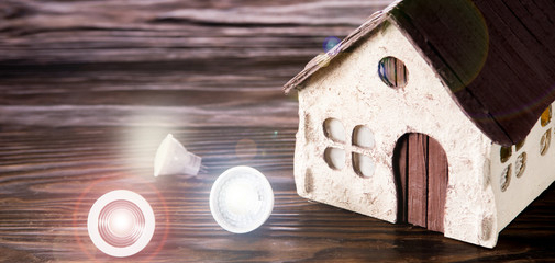 Led lamps lie near the house layout on a wooden background