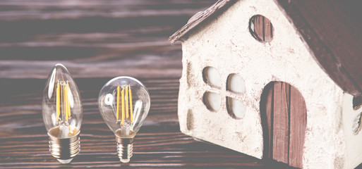 Led lamps lie near the house layout on a wooden background