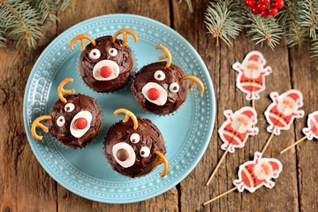Obraz na płótnie Canvas Homemade funny cupcakes Santa's reindeers on a wooden background. Christmas idea for kids.