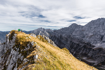 Fototapeta premium Drei Wanderer am Torkopf im Karwendelgebirge, rechts Stuhlkopf und Tafelespitze, Tirol, Österreich.