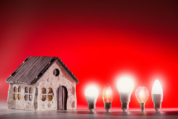 Led lamps stands near the house layout on a red background.