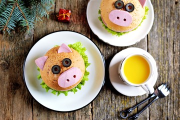 Sandwich with ham, cheese and lettuce in the form of cute pig - symbol of 2019. Children's breakfast. Christmas background. Top view.