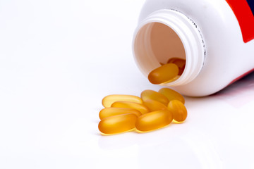 Fish oil on golden capsule on white isolated background.