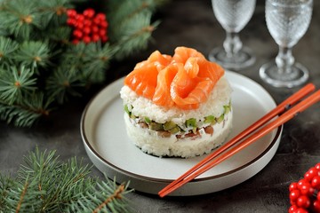 Homemade sushi cake with lightly salted salmon, avocado, soft cheese and seaweed. Christmas background.