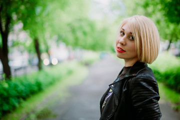 Portrait of a blonde girl walking in a green park