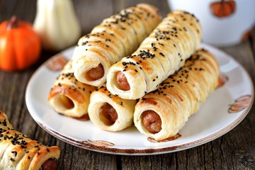 Homemade sausages in puff pastry on wooden background.