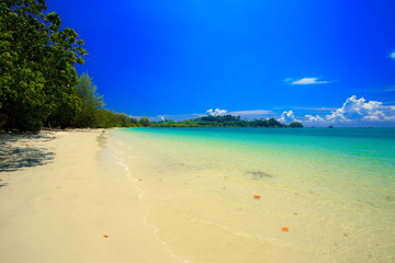 Fototapeta premium A fishing boat floating on beach with clean and clear sea and cloudy blue sky. Copy space. 