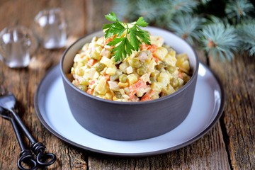 Traditional Russian salad Olivier on an old wooden background. Russian kitchen. Rustic style.
