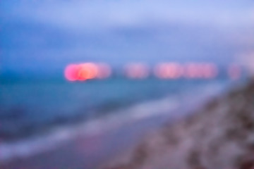 Sunny Isles Beach evening in Miami, Florida with sand, pier, waves crashing on shore coastline, colorful turquoise water, bokeh abstract background circles, illuminated red blurry blurred