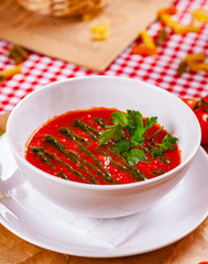 Tomato cold gazpacho soup with pesto sauce in white bowl. Close up
