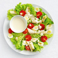 calamari salad with lettuce, tomatoes, and quile eggs dressed with mayonnaise based sauce 